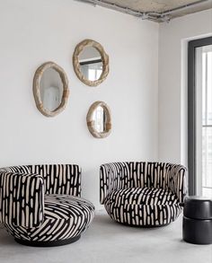 a living room with two chairs and mirrors on the wall next to eachother