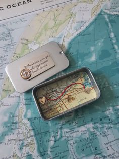 a small metal box with a map and compass on it sitting on top of a map