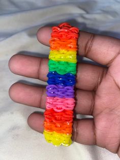 a person holding a rainbow colored bracelet in their hand