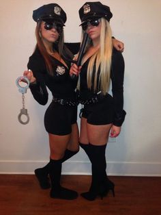 two women dressed up as police officers with handcuffs on their hands and one holding a bottle opener