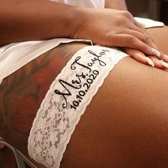 a woman with tattoos on her back has a piece of white lace around her leg