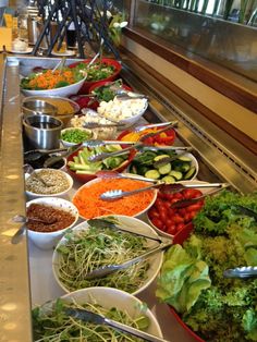 a buffet line filled with lots of different types of food and salads on plates