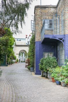 an old brick building with potted plants on the sidewalk