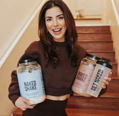 a woman holding two jars of naked shake