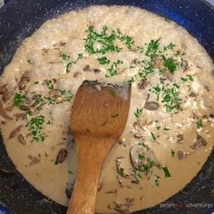 a wooden spoon in a skillet filled with mushroom risols and broth