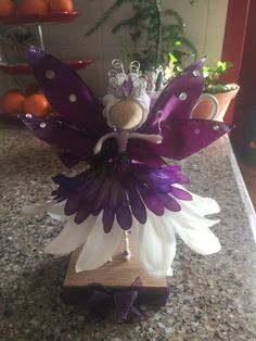 a purple and white flower fairy sitting on top of a counter