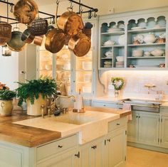 a kitchen filled with lots of pots and pans hanging from the ceiling next to a sink