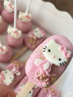 hello kitty cake pops on a stick with gold sprinkles and pink frosting