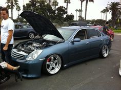 a man standing next to a blue car with its hood open