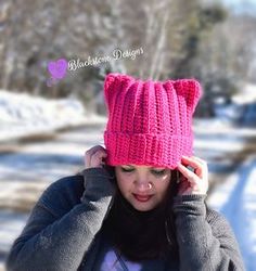 a young woman wearing a pink knitted hat while holding her hands to her head