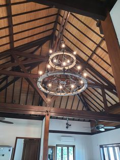 a chandelier hanging from the ceiling in a room with wood beams and windows