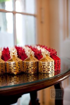 red and gold boxes with bows are on a glass table in front of a window