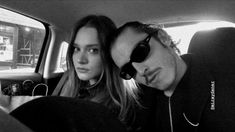 a man and woman are sitting in the back seat of a car with sunglasses on