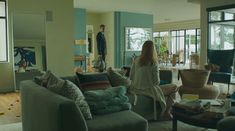 a woman standing in a living room next to a couch