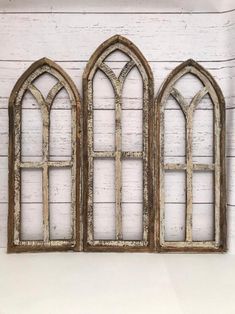 an old window with three arched windows on the side of a white brick wall in front of a wooden planked wall