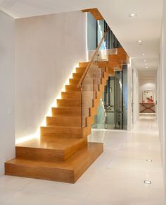 a wooden stair case with lights on the bottom and sides in a modern style home