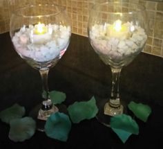 two wine glasses filled with marshmallows and lit candles sitting on a counter