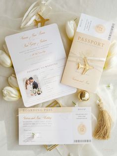 the wedding stationery is laid out on top of white tulips and gold foil