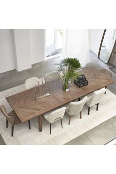 a dining table with chairs and a plant on top of it in an open room