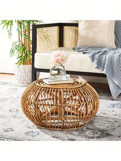 a wicker table with a flower on it in front of a couch and rug