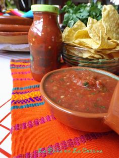 a bowl of salsa and tortilla chips on a table with other mexican foods