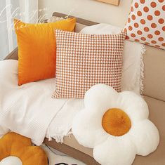 a couch with some pillows on it and a flower in the corner next to them