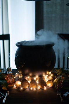 a caulder sitting on top of a table covered in candles and fairy lights