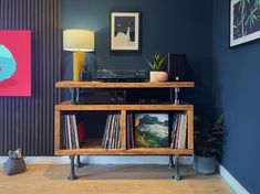 a record player sitting on top of a wooden shelf next to a wall with pictures