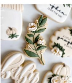 decorated cookies with leaves and flowers are on a white tablecloth next to the cookie cutters