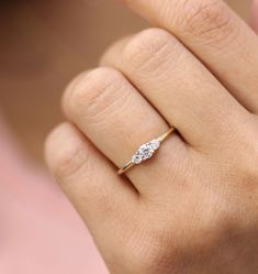 a woman's hand with a diamond ring on top of her finger, showing the side view