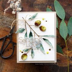 a close up of a card on a table with some scissors and leaves next to it