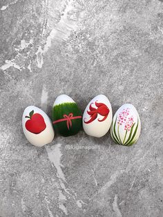 four painted eggs with designs on them sitting in the middle of a stone floor,