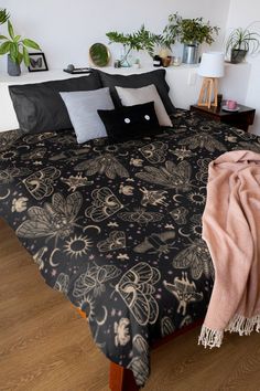 a black and white bedspread with a cat on it's face in front of some potted plants