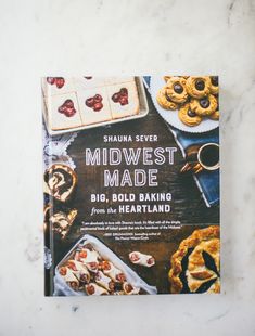 the book is sitting on top of a marble table with cookies and other desserts