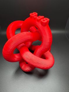 a red sculpture is sitting on a black surface