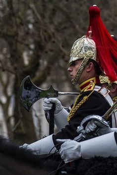 a man riding on the back of a horse wearing a red and gold helmet with horns