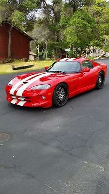 a red and white striped sports car parked on the side of the road in front of a house