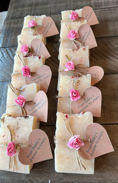 several soap bars with pink flowers and hearts tied to them on top of a wooden table