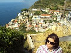 a woman standing on top of a hill next to the ocean