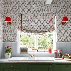 a kitchen with green cabinets and red lamps on the window sill above the sink