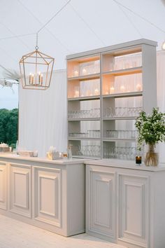 a kitchen with white cabinets and lights on the ceiling is lit up by candles that are hanging from the ceiling