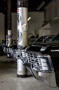 several cars are parked in a garage with their hoods painted black and white,