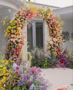 an arch made out of flowers in front of a house