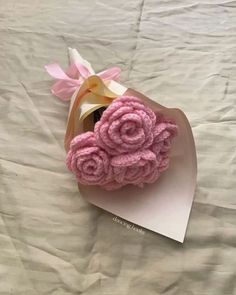 pink crocheted roses are placed on top of a folded card and tied to a ribbon