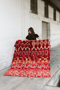 a woman holding up a red and black blanket