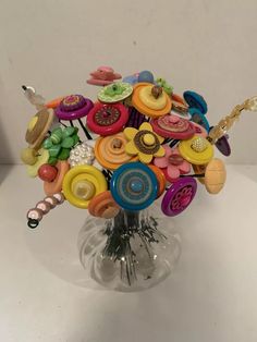 a glass vase filled with lots of colorful buttons and pins on it's sides