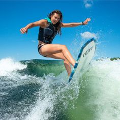 a woman riding a surfboard on top of a wave in the ocean with her arms out