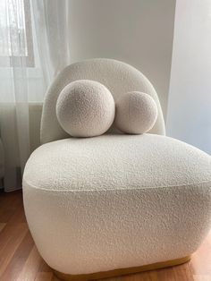 a white chair with two balls on it's back in front of a window