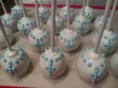 there are many white and blue cake pops on the table with candy sticks in them