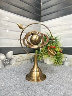 a golden metal object sitting on top of a table next to potted plants and flowers